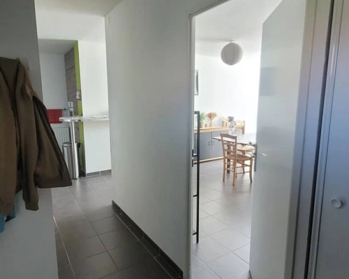 Vue du couloir avant les travaux, avec un placard blanc et une porte donnant accès au salon