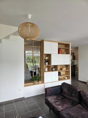 Meuble sur-mesure avec séparation entre l'entrée et le séjour, avec rangement intégré et éclairage naturel.