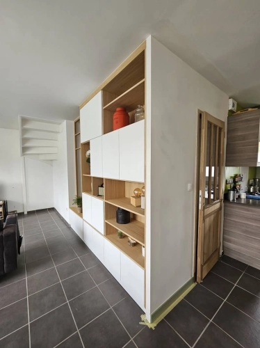Meuble sur-mesure séparant l'entrée du séjour avec des étagères ouvertes pour éléments décoratifs et rangement pratique.